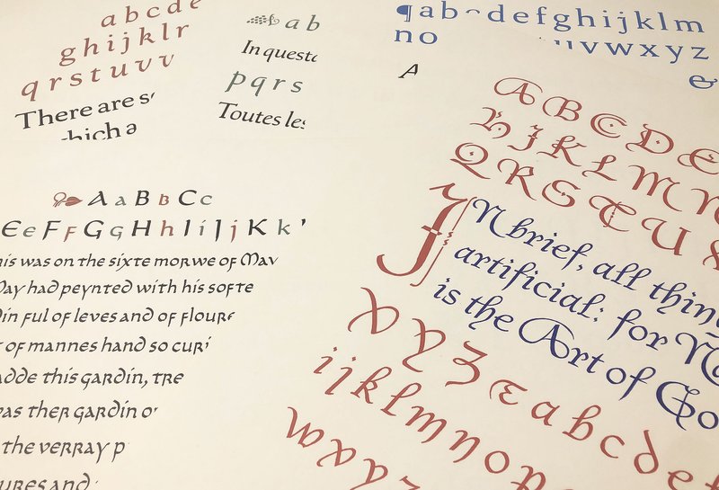 Several artistic prints of lettering samples are stacked